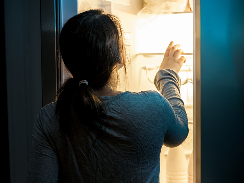 Woman looking in fridge at night